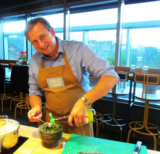 Jürgen Reibrich giesst Öl in den Stößel gefüllt mit Kräutern